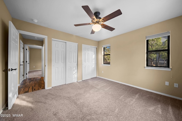 unfurnished bedroom featuring multiple closets, carpet floors, multiple windows, and baseboards