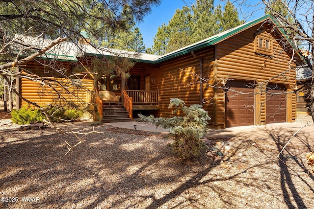 log-style house featuring a porch, concrete driveway, and metal roof