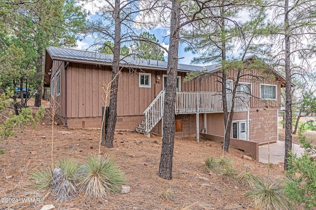 back of property with stairway, metal roof, and a deck