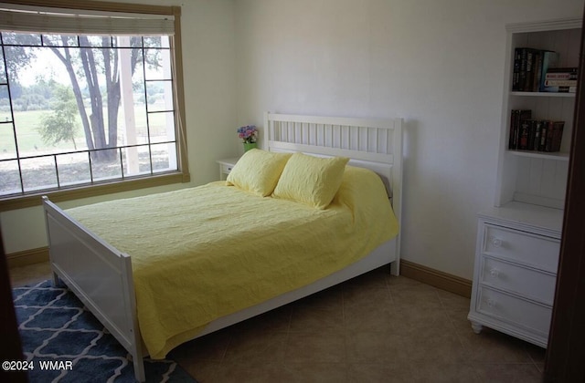 bedroom featuring multiple windows, dark tile patterned floors, and baseboards