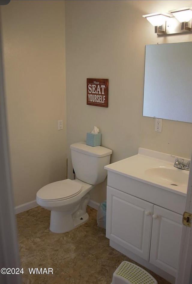 half bath featuring toilet, baseboards, and vanity