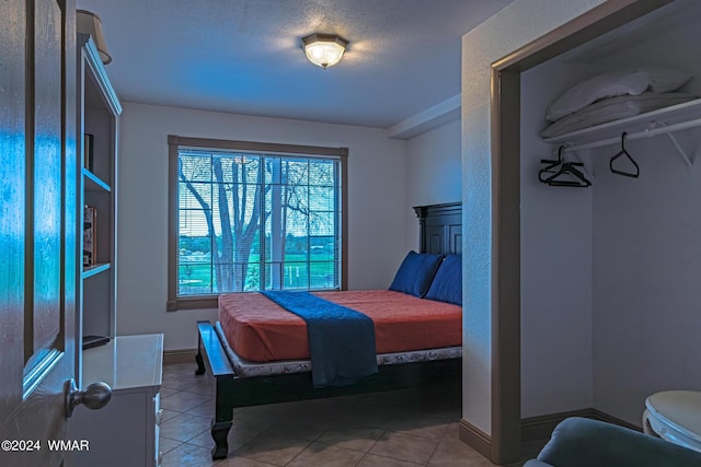 bedroom with a textured ceiling, light tile patterned flooring, and baseboards