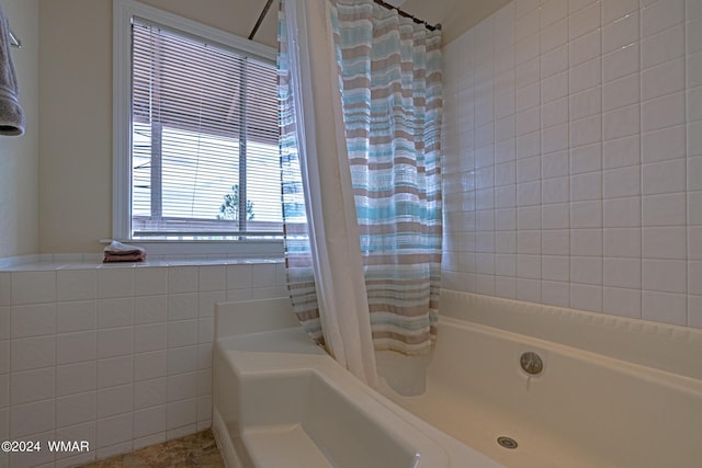 full bath featuring shower / bath combo with shower curtain and tile walls