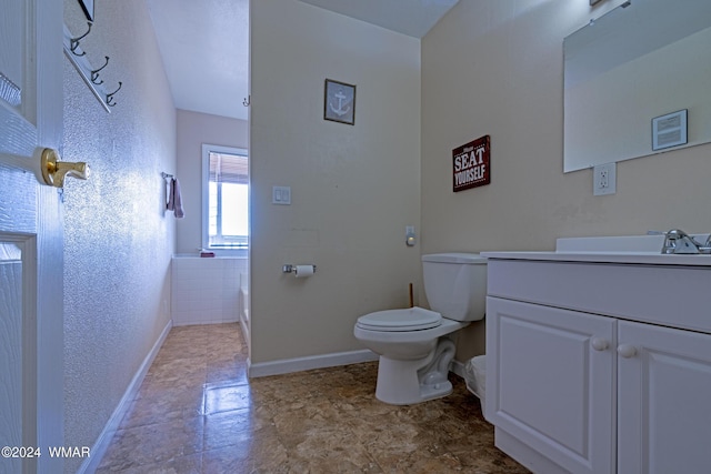 bathroom with a textured wall, vanity, toilet, and baseboards