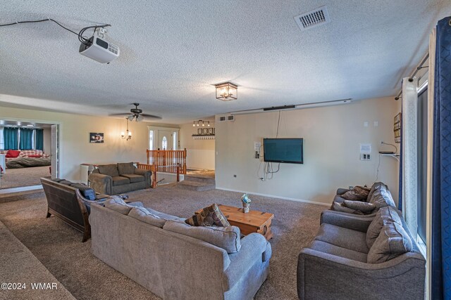 living room with baseboards, visible vents, ceiling fan, a textured ceiling, and carpet floors