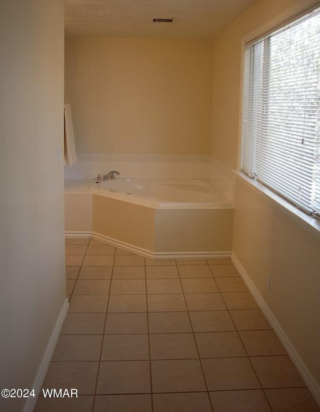 bathroom with tile patterned flooring, visible vents, baseboards, and a bath