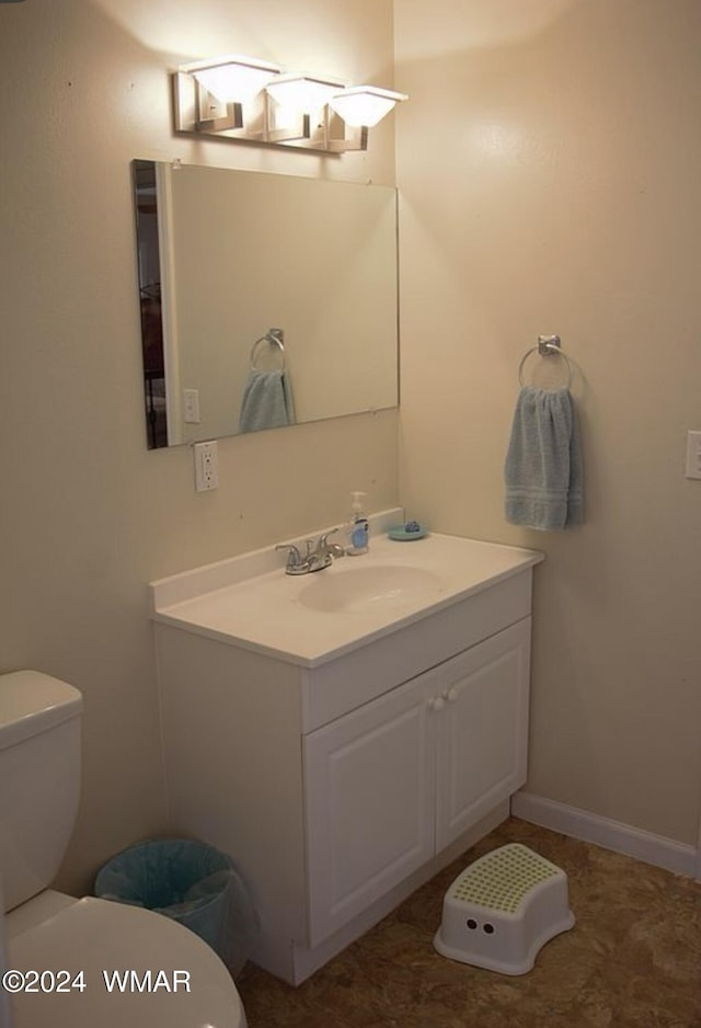 bathroom with toilet, vanity, and baseboards