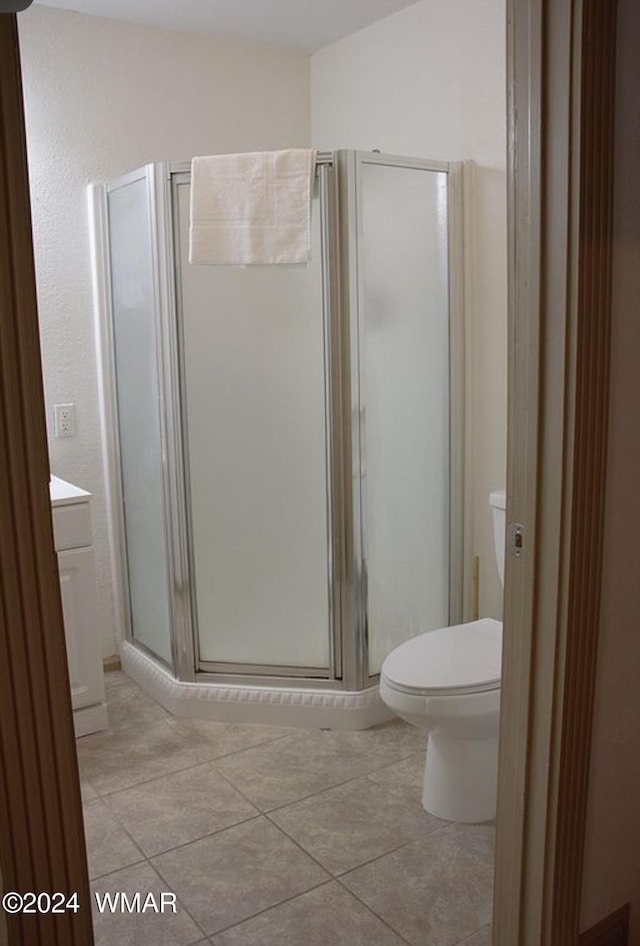 full bath featuring toilet, a stall shower, vanity, and tile patterned floors