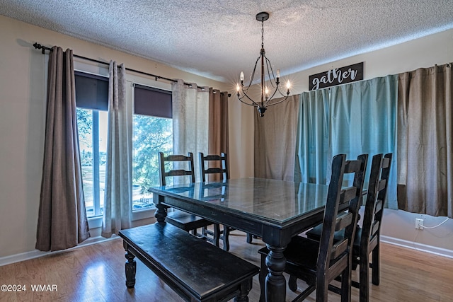 dining space featuring an inviting chandelier, a textured ceiling, and wood finished floors