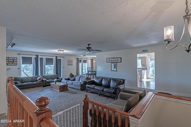 living area with an inviting chandelier, a textured ceiling, and carpet flooring