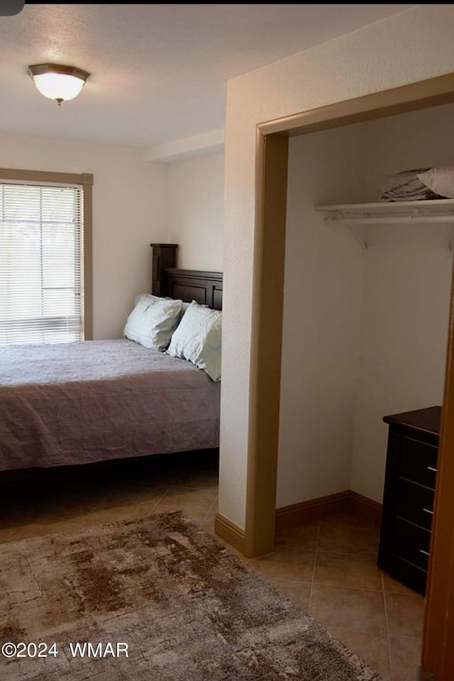 bedroom featuring tile patterned flooring, baseboards, and a closet