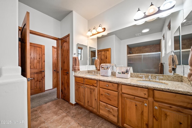 full bath with a shower stall, double vanity, visible vents, and a sink