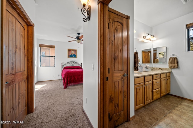 ensuite bathroom featuring vanity, ensuite bath, a ceiling fan, and baseboards