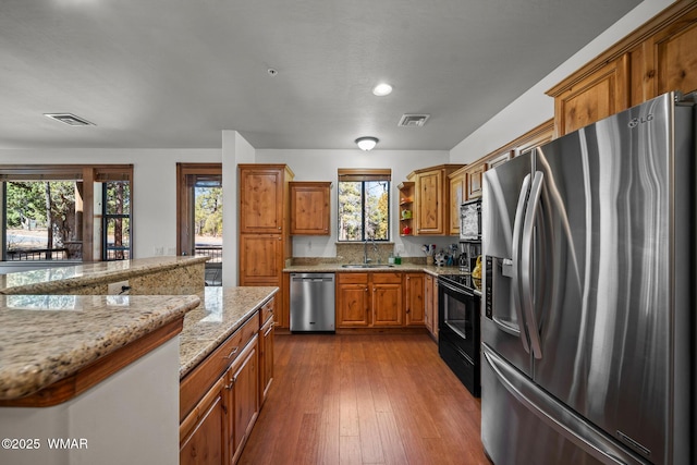 kitchen featuring brown cabinets, visible vents, appliances with stainless steel finishes, and a sink