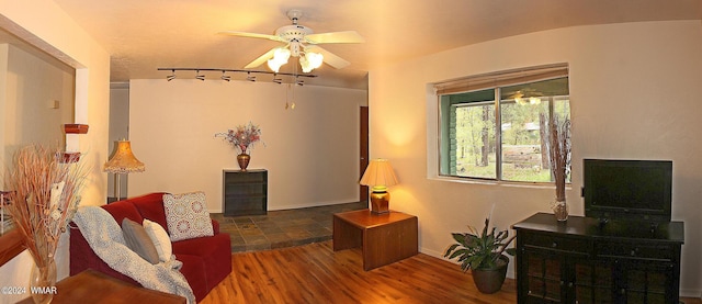 living room with dark wood-style floors, baseboards, and a ceiling fan