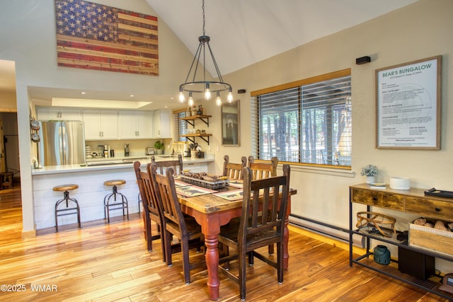 6970 Palomino Dr, Pinetop, AZ 85935 - dining space with high vaulted ceiling, a baseboard heating unit, and light wood-style floors