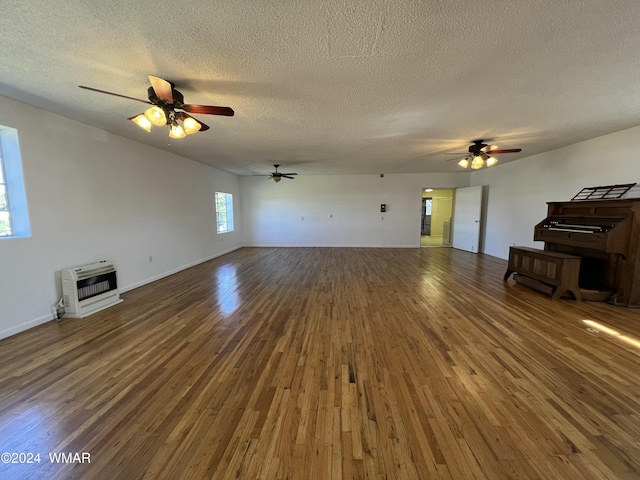 unfurnished living room with dark wood finished floors, heating unit, a ceiling fan, a textured ceiling, and baseboards