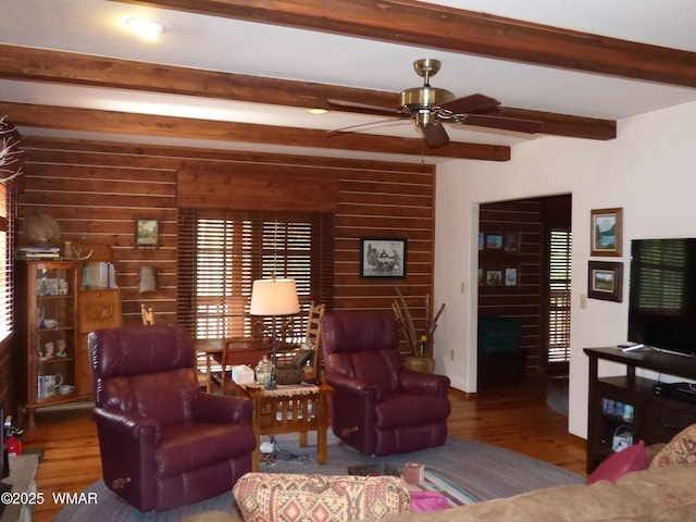 living area featuring ceiling fan, beam ceiling, and wood finished floors