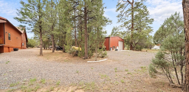 view of yard featuring a detached garage, an outbuilding, and gravel driveway