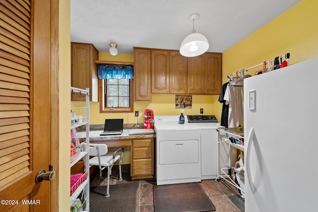 kitchen with brown cabinetry, washing machine and dryer, light countertops, and freestanding refrigerator