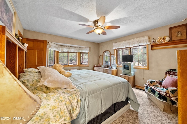 carpeted bedroom with multiple windows, a ceiling fan, and a textured ceiling