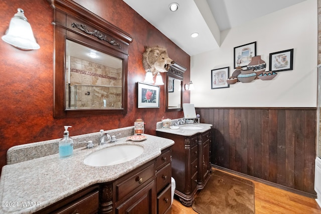 bathroom featuring a shower stall, wood finished floors, wainscoting, and a sink