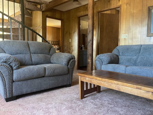 living room with light carpet, wood walls, stairs, and beamed ceiling