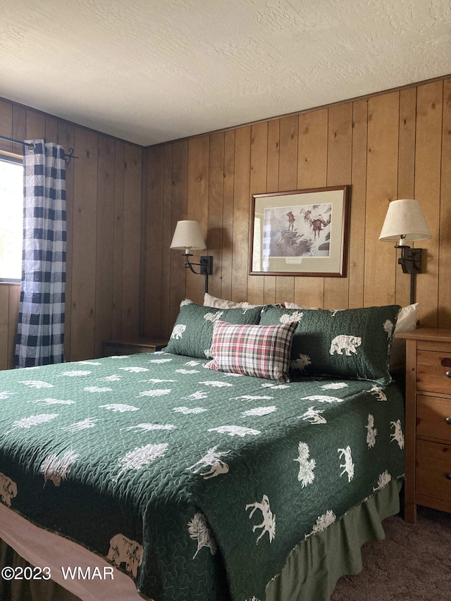 carpeted bedroom featuring a textured ceiling and wood walls