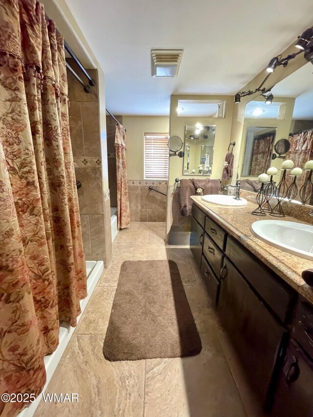 183 N Becker Lake Rd, Springerville, AZ 85938 - full bathroom featuring tile walls, a tile shower, double vanity, and wainscoting