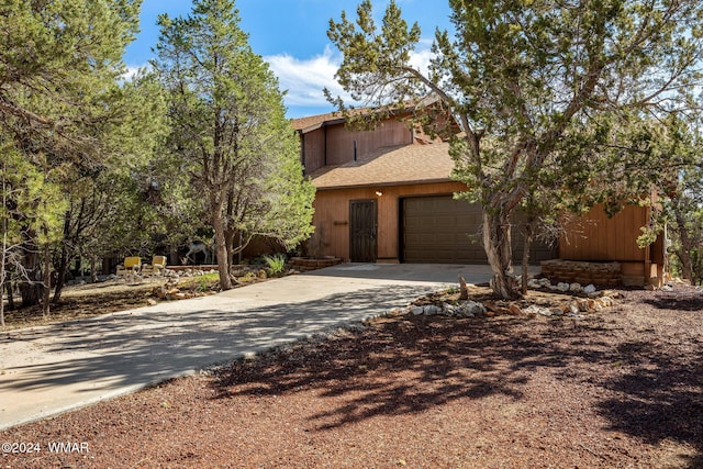 view of front of property featuring concrete driveway, roof with shingles, and an attached garage