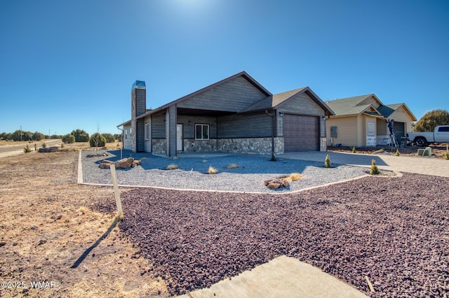 view of front of home featuring a garage, stone siding, a chimney, and concrete driveway