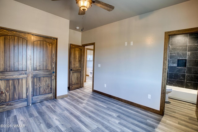 unfurnished bedroom featuring light wood-type flooring, ensuite bath, baseboards, and ceiling fan