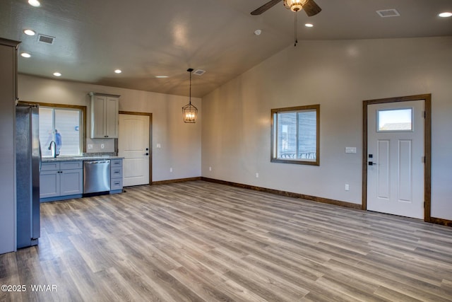 kitchen with visible vents, appliances with stainless steel finishes, decorative light fixtures, light wood-style floors, and a sink