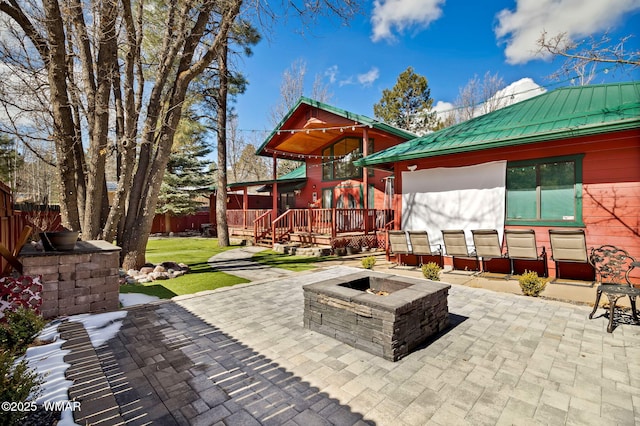 view of patio / terrace with a wooden deck, a fire pit, and fence