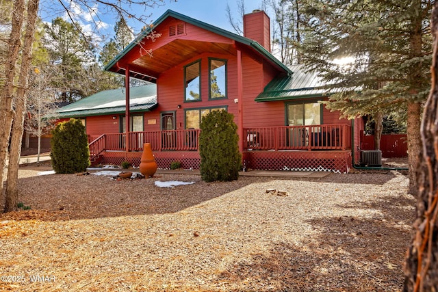 back of house featuring a chimney, central AC unit, and metal roof