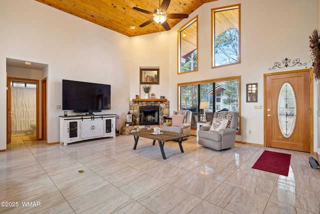 living area featuring baseboards, wooden ceiling, a fireplace, marble finish floor, and a ceiling fan