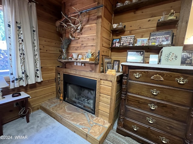 interior space with a fireplace with raised hearth and wooden walls