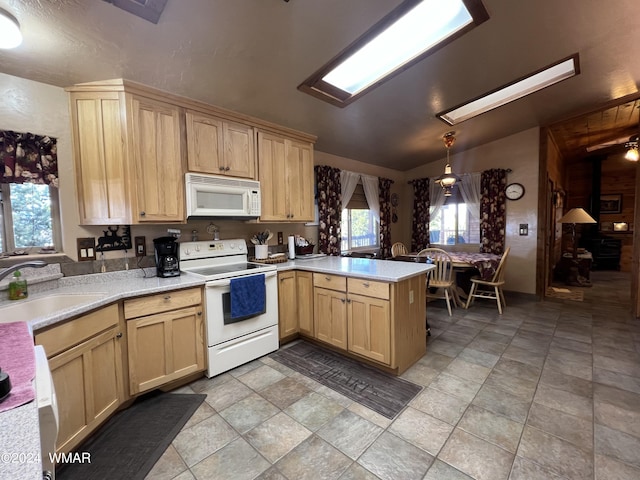 kitchen featuring light countertops, light brown cabinets, a sink, white appliances, and a peninsula