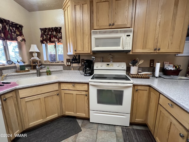 kitchen with white appliances, light countertops, a sink, and light brown cabinets