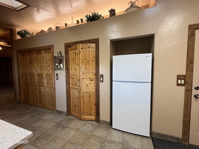 kitchen with freestanding refrigerator, a textured wall, and baseboards