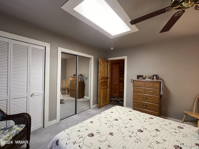 bedroom with baseboards, ceiling fan, light colored carpet, and multiple closets