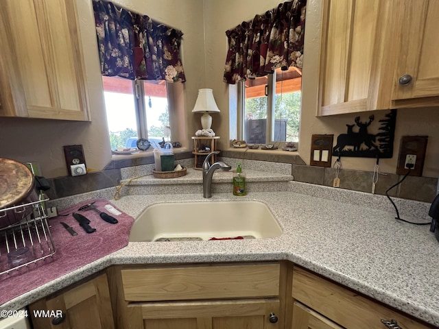 kitchen featuring light brown cabinetry, light stone counters, and a sink