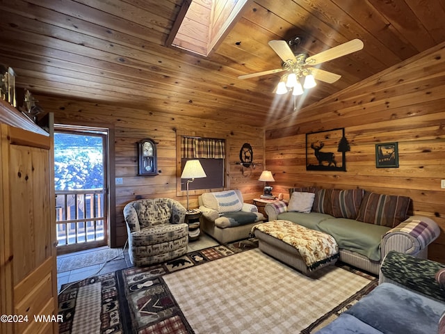 living room with vaulted ceiling with skylight, wooden ceiling, ceiling fan, and wooden walls