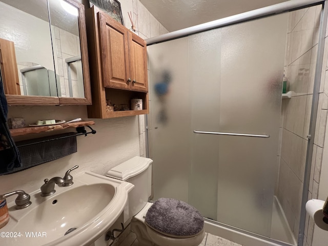 bathroom featuring a stall shower, a sink, and toilet