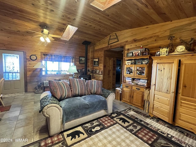 living area featuring wood ceiling, lofted ceiling with skylight, wood walls, and a wood stove