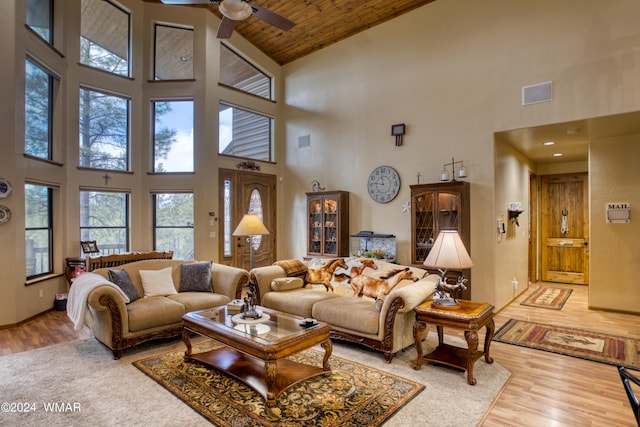 living area featuring visible vents, a ceiling fan, wooden ceiling, wood finished floors, and a high ceiling