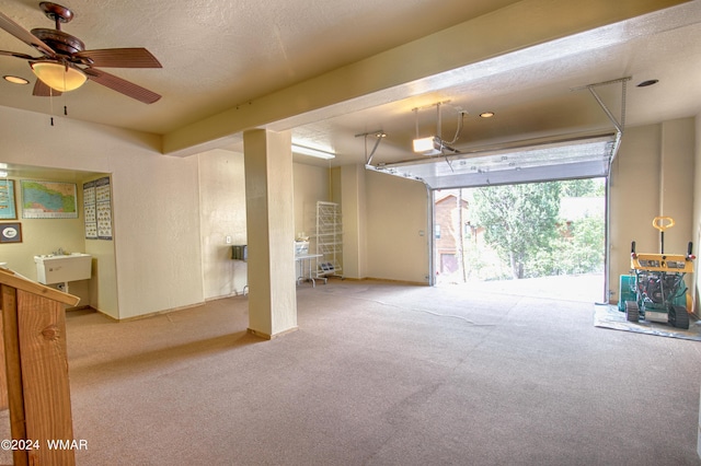 garage featuring ceiling fan, a sink, and a garage door opener