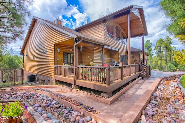 view of home's exterior featuring faux log siding, roof with shingles, a chimney, and central AC unit