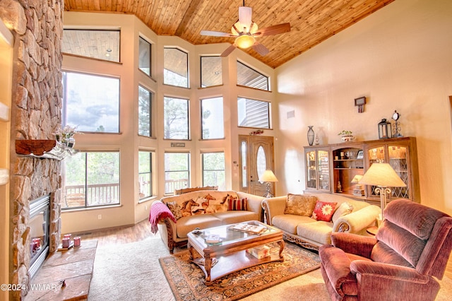 living area featuring wooden ceiling, ceiling fan, light wood-style floors, a fireplace, and high vaulted ceiling