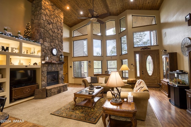 living room with a healthy amount of sunlight, wood ceiling, wood finished floors, and a stone fireplace